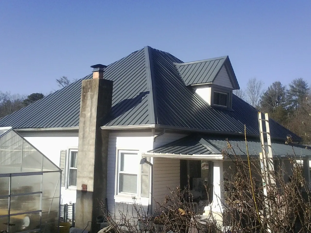 Dark blue standing seam metal roof on a white farmhouse with dormer — Slate & Tile Roof Repair by Roofing Brothers in Palatine
