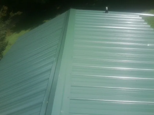 New green metal panels meeting at the ridge of a roof — Flat Roof Repair work by our crew in Palatine