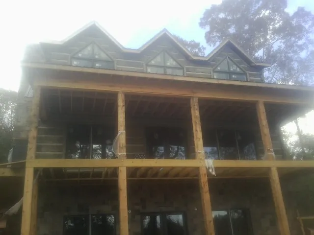Dormers and porch framing on a large log home under construction — Roof Coating work by our crew in Palatine