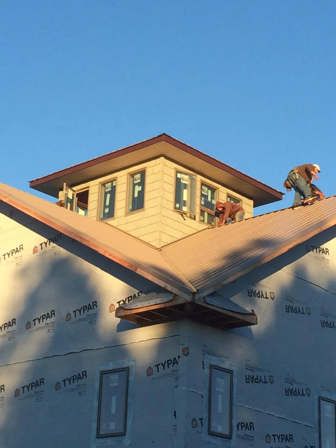 Roofers working around a rooftop cupola on a new metal roof at sunset — Roof Waterproofing in Palatine by Roofing Brothers